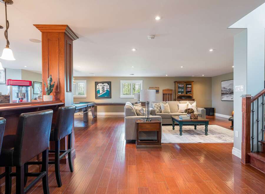 This finished basement offers a perfect blend of entertainment and relaxation, featuring a full-service bar with seating and a dedicated game area with a pool table.