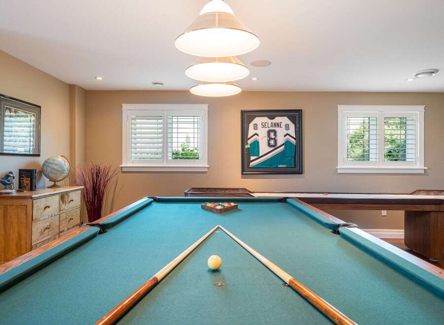 This game room features a classic pool table with a full set of balls and cues, ready for a friendly match.