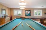 This game room features a classic pool table with a full set of balls and cues, ready for a friendly match.