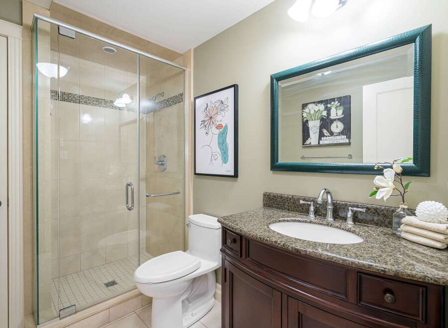 This modern bathroom features a spacious glass-enclosed shower with tiled walls and a sleek chrome showerhead.
