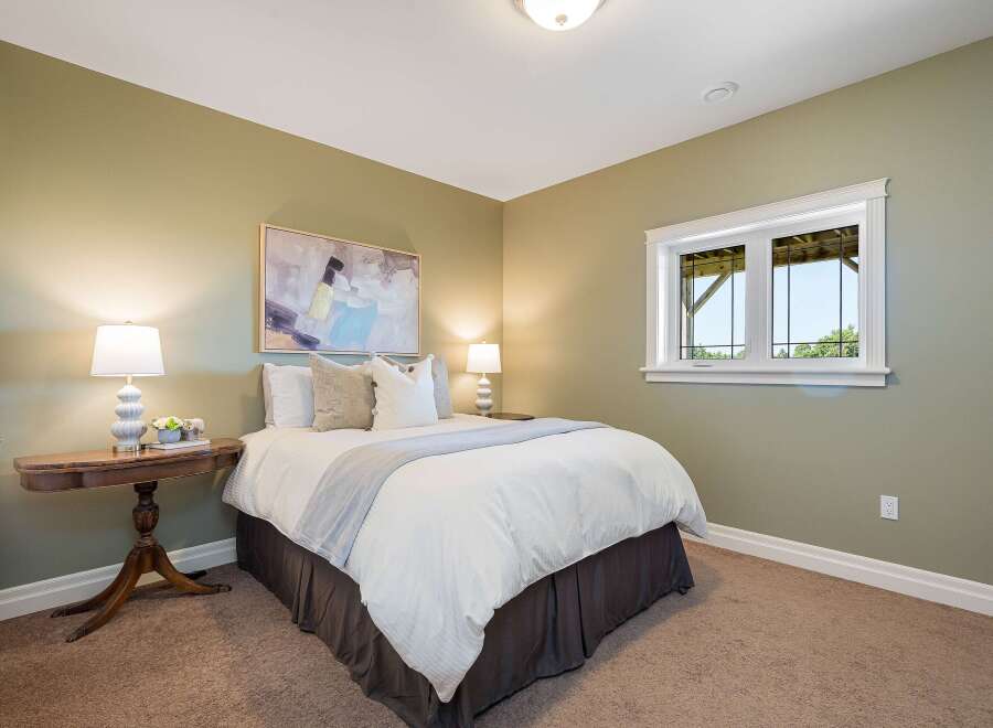 This charming bedroom features a comfortable queen-size bed with crisp white linens and a soft grey throw.
