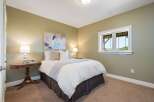 This charming bedroom features a comfortable queen-size bed with crisp white linens and a soft grey throw.