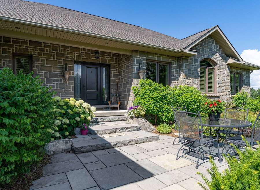 This charming home features a beautiful stone exterior and a welcoming entrance with a covered porch.