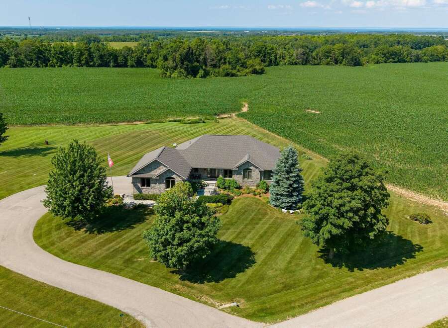 Experience serene country living in this stunning stone-clad residence, nestled amidst sprawling cornfields and manicured lawns.