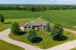 Experience serene country living in this stunning stone-clad residence, nestled amidst sprawling cornfields and manicured lawns.