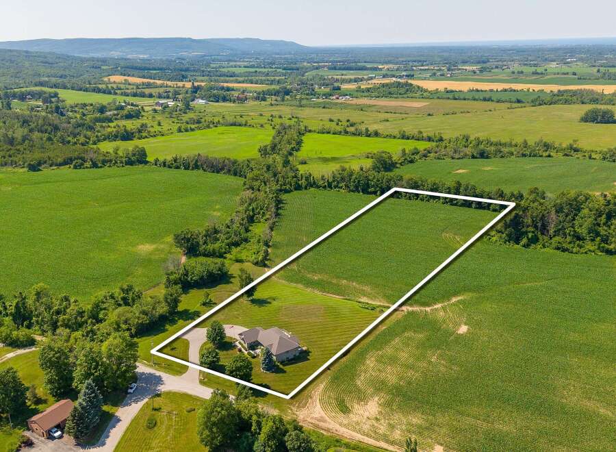 Discover this stunning property featuring a beautiful home nestled on a sprawling lot, surrounded by lush greenery and picturesque farmland.