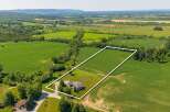 Discover this stunning property featuring a beautiful home nestled on a sprawling lot, surrounded by lush greenery and picturesque farmland.