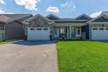Discover this stunning modern home featuring a striking stone and dark siding facade, complemented by a well-maintained lawn and a spacious driveway.