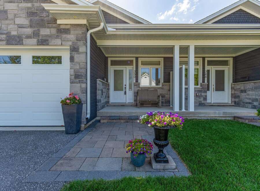 Welcome to this charming home featuring a welcoming covered porch with ample seating and beautiful floral arrangements.