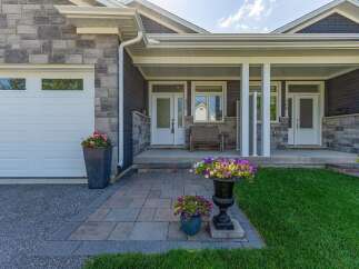 Welcome to this charming home featuring a welcoming covered porch with ample seating and beautiful floral arrangements.