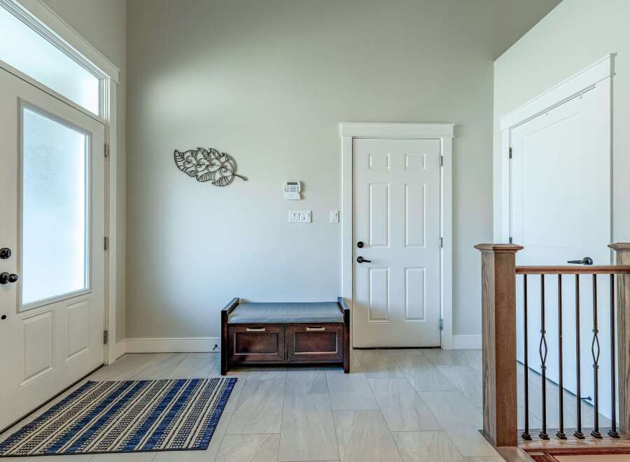 Step into this welcoming entryway featuring a frosted glass front door and a convenient storage bench.
