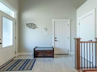 Step into this welcoming entryway featuring a frosted glass front door and a convenient storage bench.
