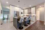 Experience modern luxury in this stunning kitchen, featuring sleek white cabinetry, a spacious island with seating, and top-of-the-line stainless steel appliances.