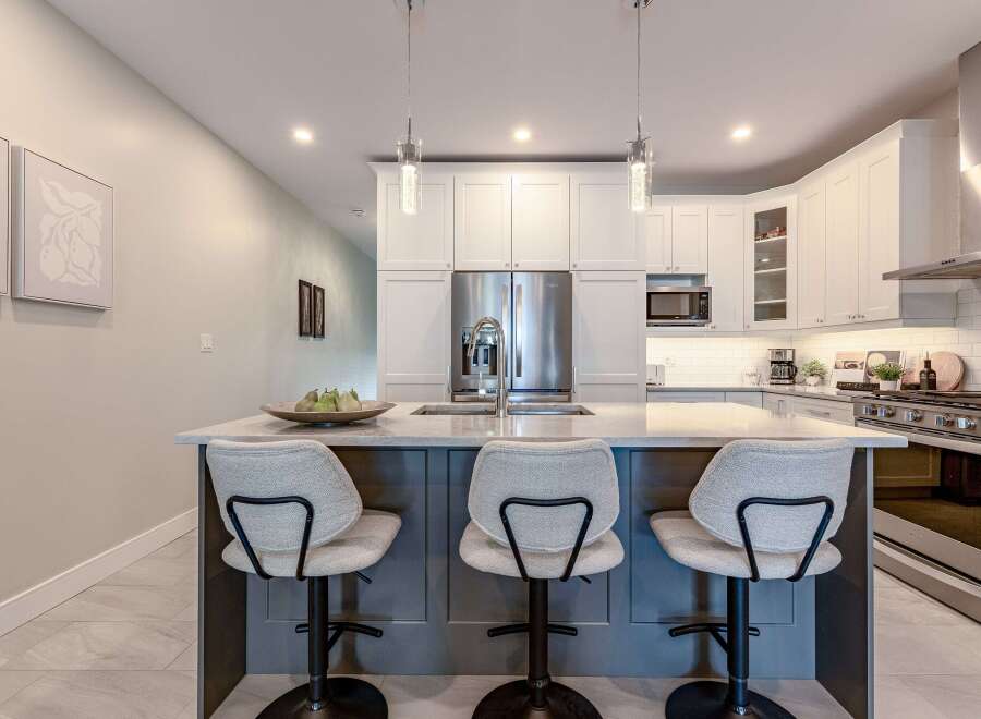 This modern kitchen boasts a sleek island with comfortable seating, perfect for casual dining or entertaining guests.