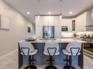 This modern kitchen boasts a sleek island with comfortable seating, perfect for casual dining or entertaining guests.