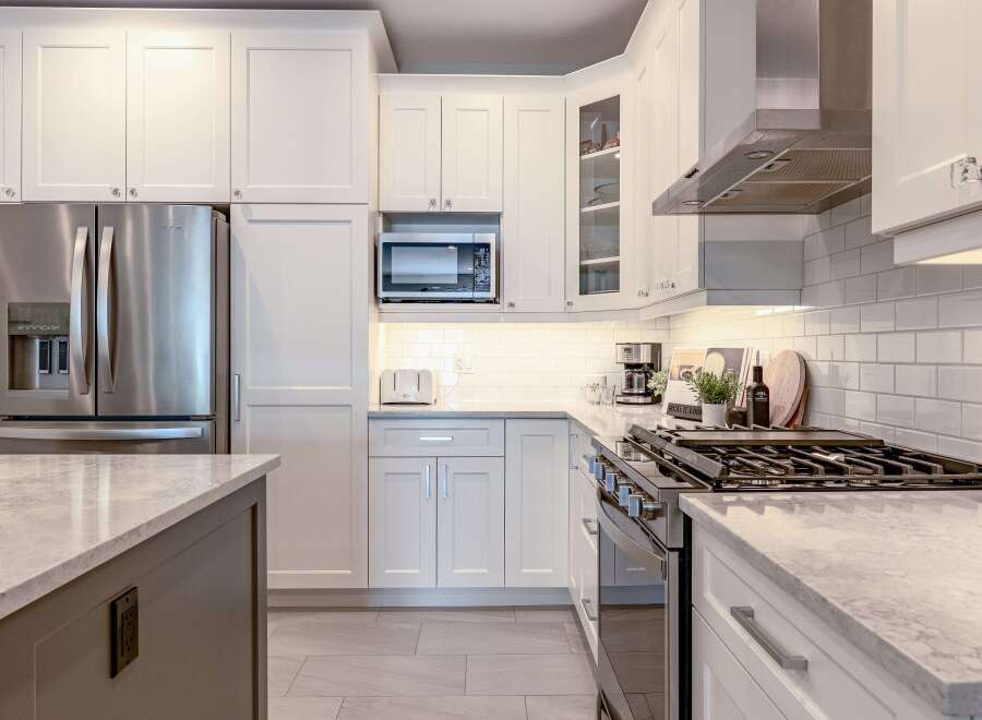 Experience modern elegance in this stunning kitchen, featuring sleek white shaker cabinets and a spacious island with a marble countertop.