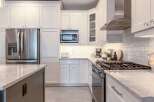 Experience modern elegance in this stunning kitchen, featuring sleek white shaker cabinets and a spacious island with a marble countertop.