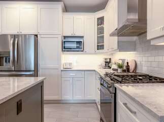 Experience modern elegance in this stunning kitchen, featuring sleek white shaker cabinets and a spacious island with a marble countertop.