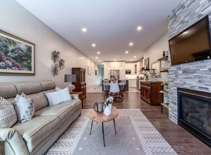 Experience modern living in this open-concept home featuring a spacious living area with a cozy fireplace and a large leather sofa.