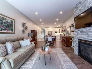 Experience modern living in this open-concept home featuring a spacious living area with a cozy fireplace and a large leather sofa.