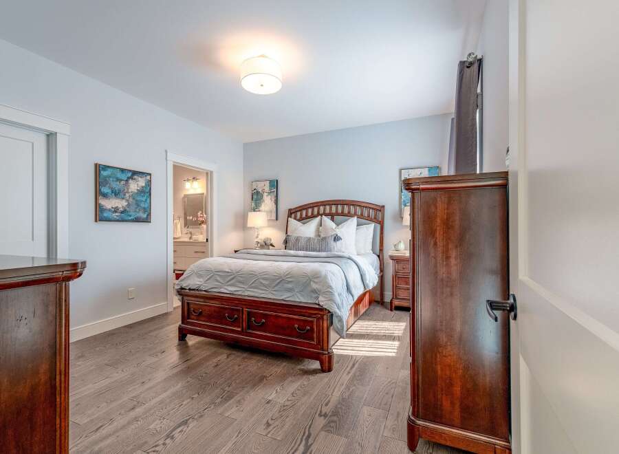 This inviting bedroom features a spacious wooden bed with ample storage drawers, complemented by elegant nightstands and a dresser.