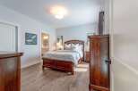 This inviting bedroom features a spacious wooden bed with ample storage drawers, complemented by elegant nightstands and a dresser.