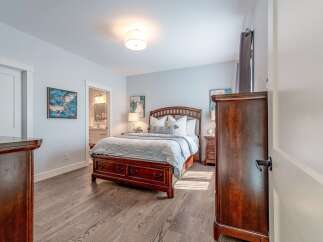 This inviting bedroom features a spacious wooden bed with ample storage drawers, complemented by elegant nightstands and a dresser.