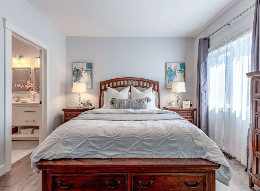 Experience ultimate comfort in this beautifully appointed bedroom, featuring a luxurious wooden bed frame and plush bedding.