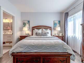 Experience ultimate comfort in this beautifully appointed bedroom, featuring a luxurious wooden bed frame and plush bedding.