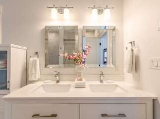 This modern bathroom features a spacious double vanity with sleek chrome faucets and a decorative floral arrangement.
