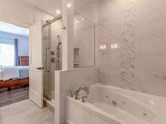 Indulge in luxury with this stunning bathroom featuring a spacious jacuzzi tub and a separate glass-enclosed shower.