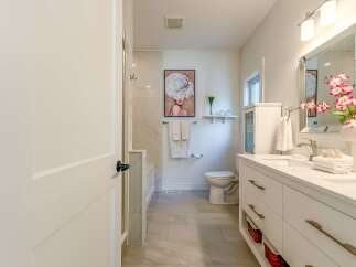 Step into this beautifully appointed bathroom featuring a spacious double vanity with sleek brass hardware and ample storage.