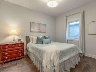 Discover comfort and style in this charming bedroom, featuring a queen-sized bed adorned with decorative pillows and a cozy throw.