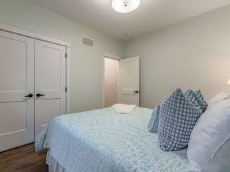 Discover this charming bedroom featuring a comfortable bed adorned with a stylish blue and white patterned comforter and plush decorative pillows.