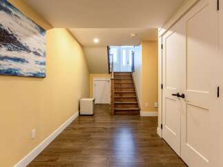 Discover this charming home featuring a bright and airy hallway with warm yellow walls and rich wood-look flooring.
