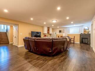 Discover this beautifully finished basement featuring a spacious living area with a large sectional sofa and a modern fireplace.