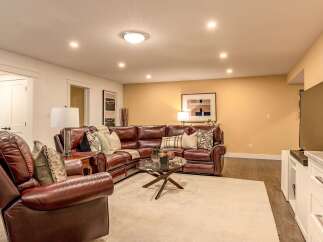 Experience ultimate comfort in this inviting living space, featuring a luxurious deep brown leather sectional sofa and a matching recliner.
