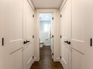 Step into a beautifully designed hallway featuring crisp white doors with modern black hardware, leading to a well-appointed bathroom.
