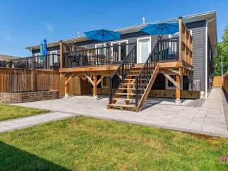 Enjoy outdoor living with this spacious deck featuring two blue umbrellas, perfect for shaded relaxation.