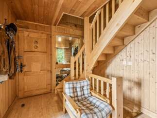 Step into this charming wooden cabin, featuring a cozy armchair perfect for relaxing after a day of adventure.