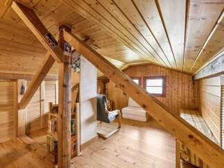 Discover this charming attic space, featuring warm wooden paneling and exposed beams that create a cozy, rustic ambiance.