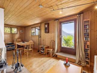 Experience cozy living in this charming wooden cabin, featuring a rustic dining area perfect for family meals and a stone fireplace for warm evenings.