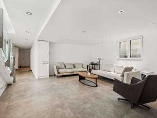 Discover modern living in this spacious open-concept living area, featuring a sleek sectional sofa and a comfortable accent chair perfect for relaxation.