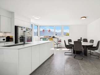 Experience modern living in this spacious kitchen and dining area, featuring a sleek white island and a round marble-top dining table perfect for gatherings.