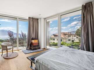 Experience breathtaking lake and mountain views from this stunning bedroom, featuring expansive floor-to-ceiling windows that flood the space with natural light.