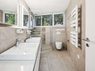 Experience modern luxury in this stunning bathroom, featuring dual vessel sinks atop a sleek vanity and a spacious glass-enclosed shower.
