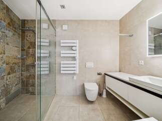 Experience modern luxury in this stunning bathroom featuring a spacious walk-in shower with unique, textured tilework.