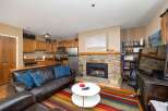 Cozy living room featuring a plush leather sofa with blue accent pillows, centered around a striking stone fireplace.