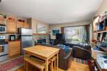Cozy living space featuring a functional kitchen with stainless steel appliances and ample cabinet storage, adjacent to a dining area with a wooden table and benches.