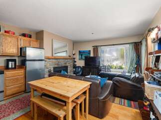 Cozy living space featuring a functional kitchen with stainless steel appliances and ample cabinet storage, adjacent to a dining area with a wooden table and benches.